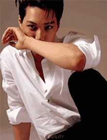 a man wearing a white shirt is kneeling down with his hand on his face