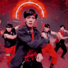 a group of young men are dancing together on a stage in front of a red light .