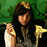 a woman smoking a cigarette with a green wall in the background