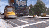 a yellow school bus is driving down a city street in front of a pizza restaurant .