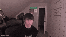 a young man is sitting in a room with a microphone in front of a door .