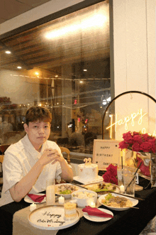 a man sits at a table with plates of food and a sign that says happy birthday dan