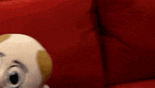 a stuffed toy with a mustache is sitting on a red chair