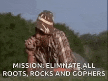 a man in a hat is smoking a cigarette in a field with the words `` mission : eliminate all roots