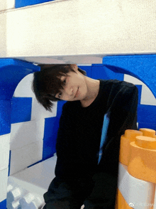 a young man in a black shirt is standing in a room with blue and white walls