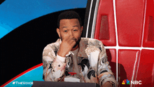 a man sitting in front of a nbc sign