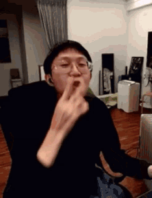 a man wearing glasses is making a funny face while sitting in a chair .
