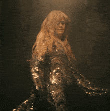a woman with long blonde hair is wearing a sequined dress with a plunging neckline