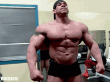 a man flexing his muscles in a gym with the word muscul on the bottom right