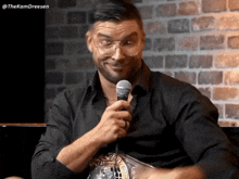 a man wearing glasses is holding a microphone in his hand