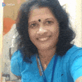 a woman in a blue shirt is smiling and wearing a lanyard with the word school on it .
