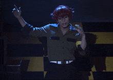 a man with red hair is dancing on a stage in a dark room