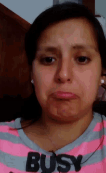 a woman wearing a pink striped shirt that says busy