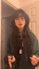 the girl is wearing a green jacket and headphones and is standing in front of a door .