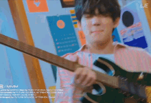 a man is playing a guitar in front of a wall that has lje written on it