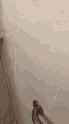 a person is holding a hammer against a wall .