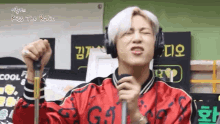 a man in a red jacket is singing into a microphone while wearing headphones .