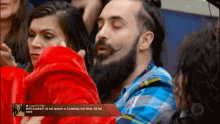 a man with a beard and mustache is sitting in a crowd of people