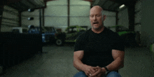 a man in a black shirt is sitting in a garage