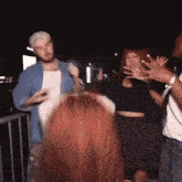 a group of people are dancing in a dark room with a man wearing a hat that says ' a ' on it