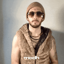 a man wearing sunglasses and a fur vest has the word mcdh on the bottom right