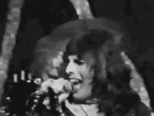 a black and white photo of a man with long hair making a face .