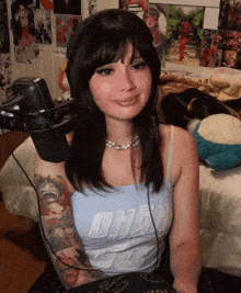 a woman is sitting in front of a microphone wearing headphones and a tank top .