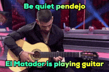 a man is playing a guitar with the words be quiet pendejo el matador is playing guitar