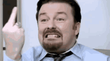 a man with a beard is wearing a blue shirt and tie and giving the middle finger .