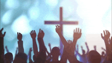 a crowd of people raising their hands in front of a cross .