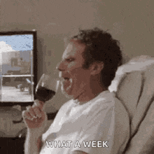 a man is sitting on a couch drinking a glass of wine and making a funny face .