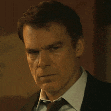a man in a suit and tie is looking at the camera with a serious look on his face
