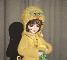 a girl wearing a duck hat and glasses is holding a stuffed duck and a frog .