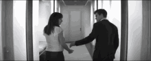 a man and woman are holding hands in a hallway