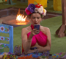 a woman with a flower crown on her head looks at her phone