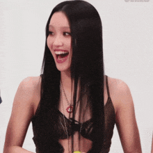 a woman with long black hair is smiling and wearing a bra