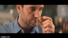 a man is smelling a cup of coffee while sitting at a table .