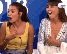 two women are sitting next to each other in front of a blue background with the number 13 on it