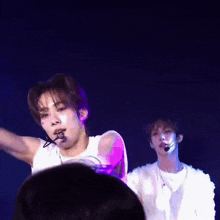a man with a microphone in his mouth is dancing on a stage .