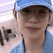 a woman wearing glasses and a blue hat looks at the camera