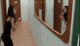a woman is standing in a hallway looking at herself in a mirror .