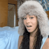 a woman wearing a fur hat is making a funny face