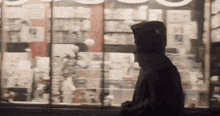 a man in a hoodie is walking past a store window .