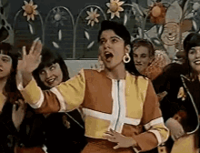 a group of women are dancing in a room with flowers on the wall .