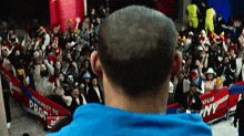 a man in a blue shirt stands in front of a crowd holding a sign that says prospect to profit