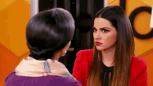 two women are standing next to each other and talking to each other .