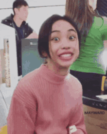 a woman in a pink sweater is making a funny face .