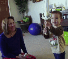 a little boy is holding a sword in front of a woman who is smiling at him ..