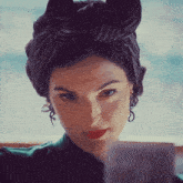 a woman wearing a turban and earrings is looking at something