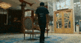 a man wearing a black geico shirt walks through a room